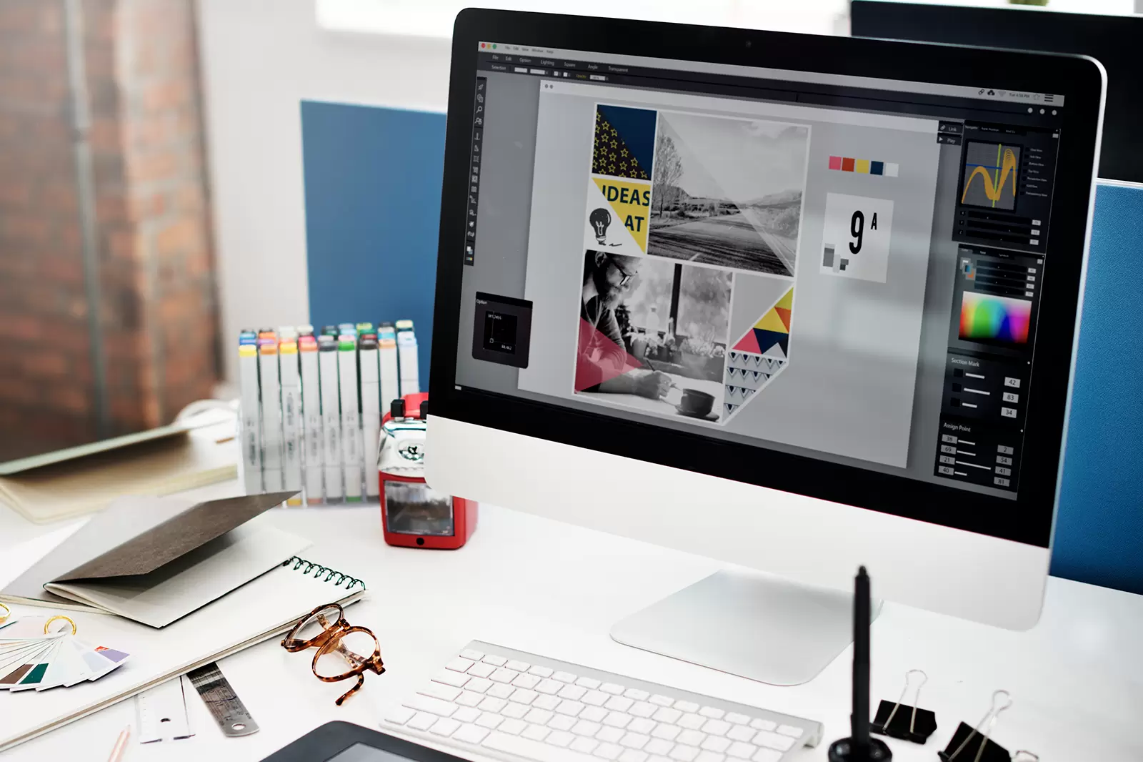ノートPCの横で紙にイラストのラフスケッチを描いている手元